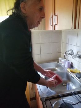Na fotografiji muškarac pere posuđe.