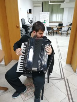 Na fotografiji se nalazi muška osoba koja svira harmoniku.