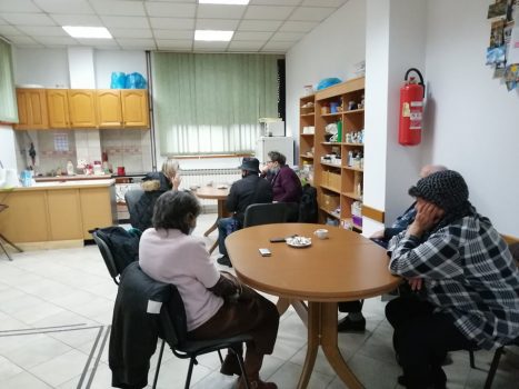 Na fotografiji se nalazi skupina ljudi koji sjede na stolicama oko stola i razgovaraju.