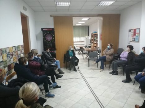 Na fotografiji skupina ljudi sjede i pričaju.