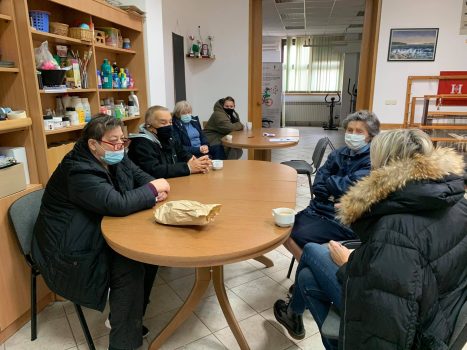 Na fotografiji se nalaze pet ženskih i jedna muška osoba, koje sjede oko stola na radionici psihosocijalne podrške.
