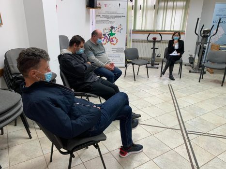 Na fotografiji tri muške i jedna ženska osoba sjede.