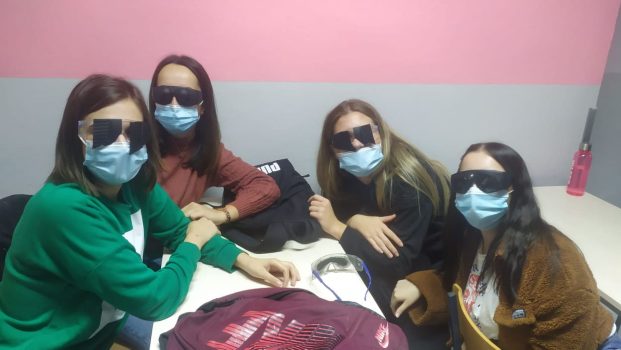 Na fotografiji se nalaze četiri mlade ženske osobe koje uz pomoć naočala dobivaju dojam kako i koliko visoko slabovidne i slijepe osobe vide ako imaju malo ostatka vida.