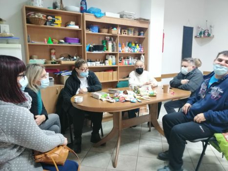 Na fotografiji se nalaze tri ženske i tri muške osobe koje sjede oko stola i razgovaraju na radionici psihosocijalne podrške.