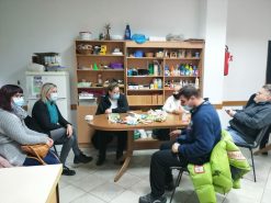 Na fotografiji tri muške i tri ženske osobe sjede oko stola i razgovaraju na radionici psihosocijalne podrške.